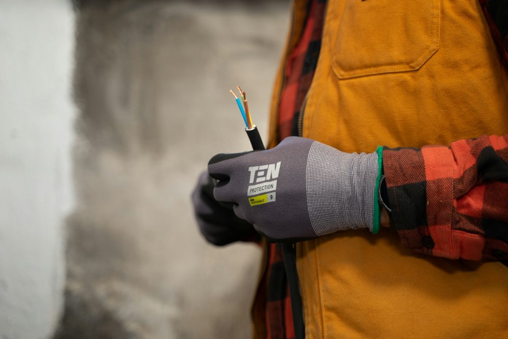 Ruka u rukavici drži električni kabel